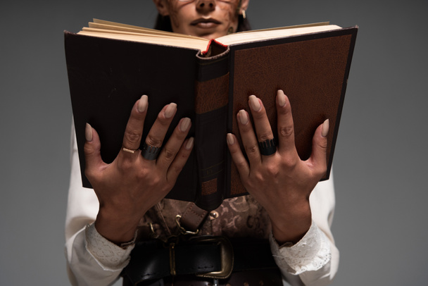 cropped view of steampunk woman reading book isolated on grey - Photo, Image
