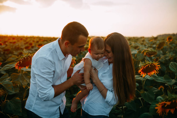 Happy family with baby has a fun and plays in the sunflower field. - Фото, зображення