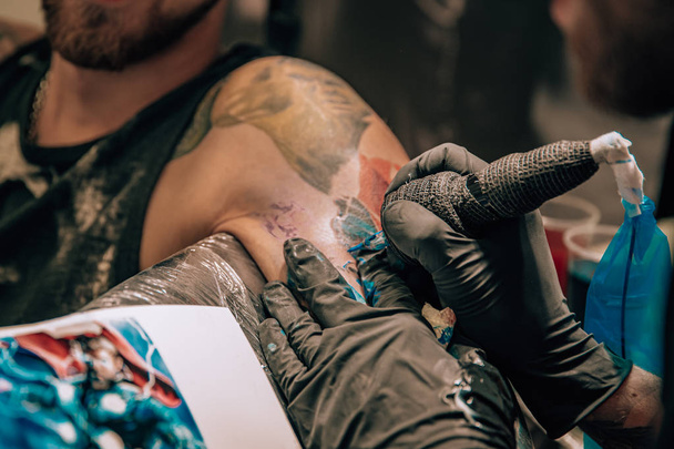 Herstellung farbiger Tattoos im Salon, Nadel auf der Haut - Foto, Bild