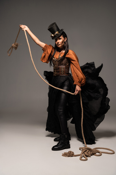 full length view of beautiful steampunk woman holding lasso on grey - Photo, Image