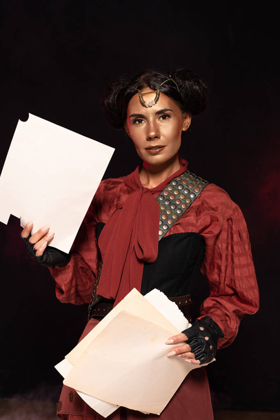 attractive steampunk young woman holding papers on black - Photo, Image