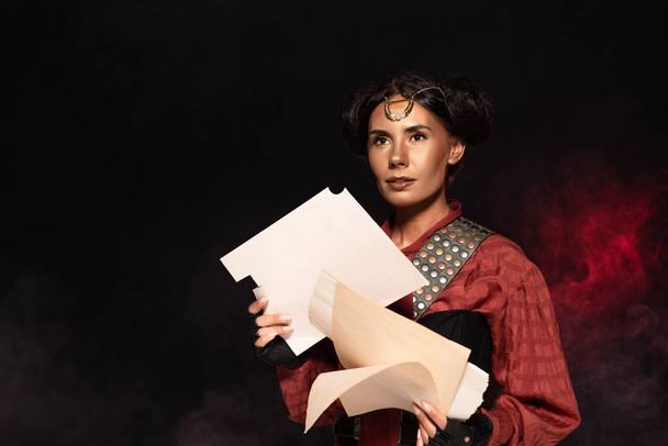 dreamy attractive steampunk young woman holding papers on black - Photo, Image
