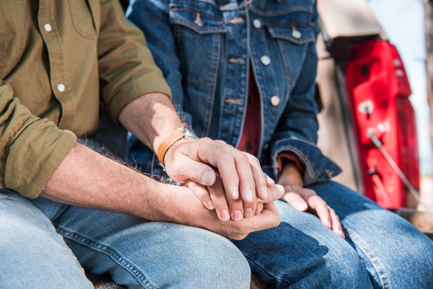 обрезанный вид пожилой пары в джинсах, держащихся за руки
 - Фото, изображение