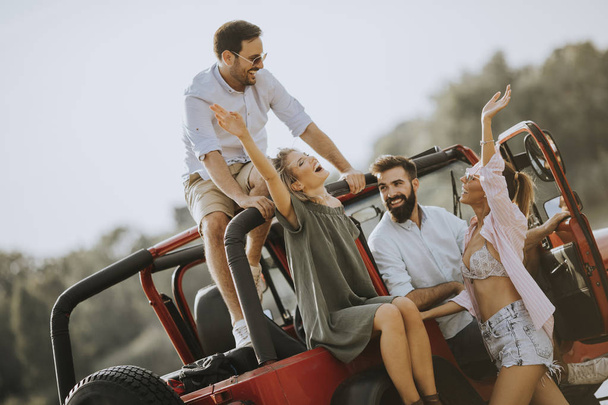 Groupe de jeunes qui s'amusent en voiture en plein air par une chaude journée d'été ensoleillée
 - Photo, image