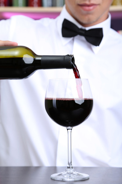 Bartender is pouring red wine into glass - Foto, Imagen