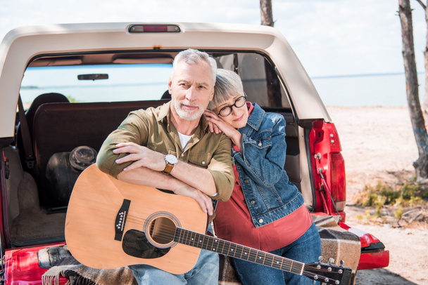 happy senior couple with acoustic guitar near car in sunny day - Fotoğraf, Görsel