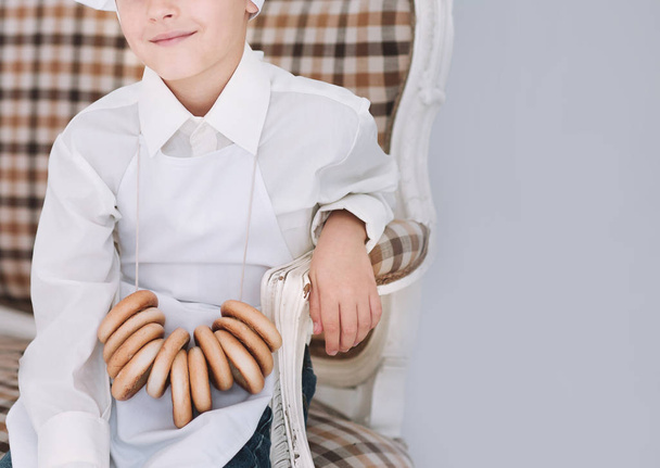 little boy in a chef uniform sitting on the kitchen couch - Foto, Imagen