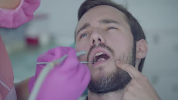Dentist in medical mask and gloves checking the tooths of the patient using medical tools. Female professional doctor stomatologist at work. Dental treatment, medical concept. Dental care. - Filmagem, Vídeo