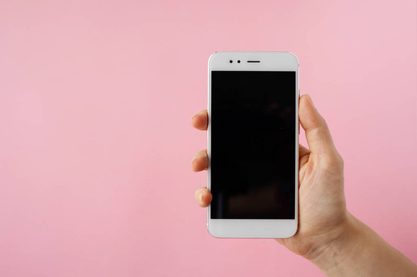 Smartphone in hand, blank screen mock up on pink background. - Photo, image