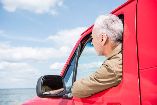 senior man looking at river from red car - Photo, Image