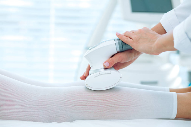 close up beauty specialist doing LPG apparatus massage on female legs - Foto, Imagem