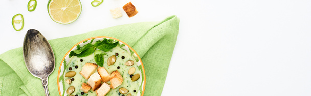 вид на вкусный сливочно-зеленый овощной суп с тыквенными семечками. мята и гренки подаются изолированными на белом, панорамном снимке
 - Фото, изображение