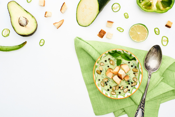 вид на вкусный сливочный суп на салфетке рядом с зелеными овощами, изолированными на белом
 - Фото, изображение