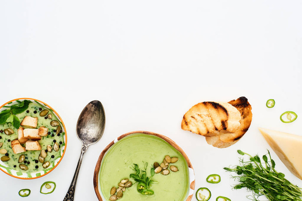 вид на вкусный сливочно-зеленый овощной суп с капустой, жареные гренки и сыр, изолированные на белом
 - Фото, изображение