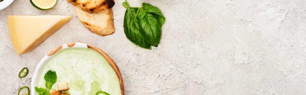 テクスチャグレーの背景にクルトンとチーズとおいしい緑のクリーミーなスープのパノラマショット - 写真・画像