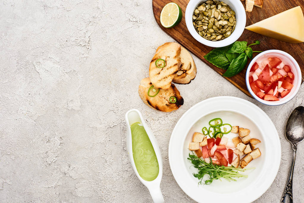 vue du dessus des ingrédients dans l'assiette près de la soupe à la crème verte et de la planche à découper en bois
 - Photo, image
