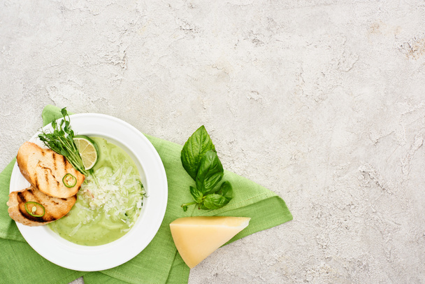 ほうれん草の葉とチーズの近くにナプキンで提供されるクルトンとおいしいクリーミーな緑の野菜スープのトップビュー - 写真・画像