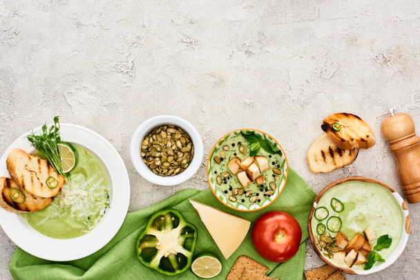 верхний вид вкусный сливочно-зеленый суп подается с овощами и гренками на зеленой салфетке
 - Фото, изображение