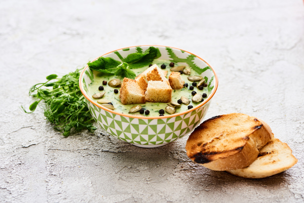 クルトン、もやし、黒コショウ、カボチャの種とおいしい緑野菜クリーミーなスープのボウル - 写真・画像