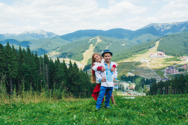 Brother and sister in national clothes in the mountains. Children travel. Beautiful boy and beautiful girl smiling in nature - Fotoğraf, Görsel