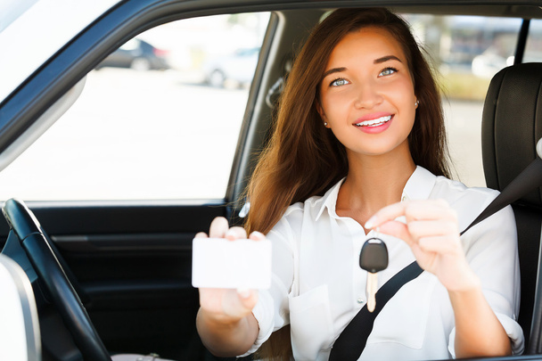 κορίτσι σε ένα αυτοκίνητο που δείχνει ένα κλειδί και μια κενή λευκή κάρτα - Φωτογραφία, εικόνα