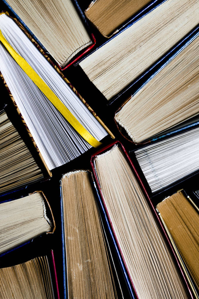 Lots of colourful thick open books stand on a dark background - Фото, зображення
