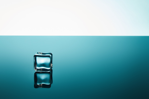transparent ice cube on emerald and white background - Foto, afbeelding