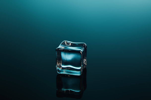 clear transparent ice cube on emerald background - Foto, imagen