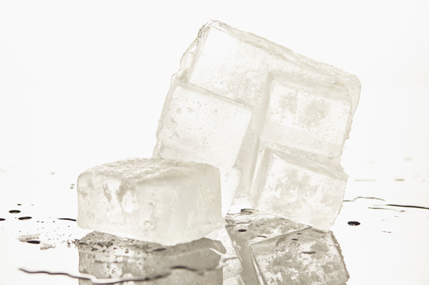 стопка прозорих талих кубиків льоду на білому фоні
 - Фото, зображення