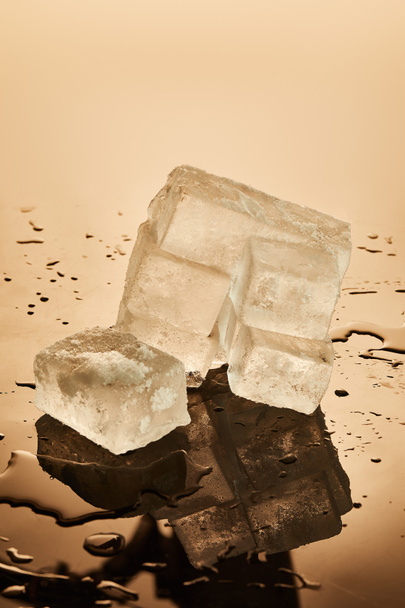 stack of transparent melting ice cubes on brown background - Φωτογραφία, εικόνα