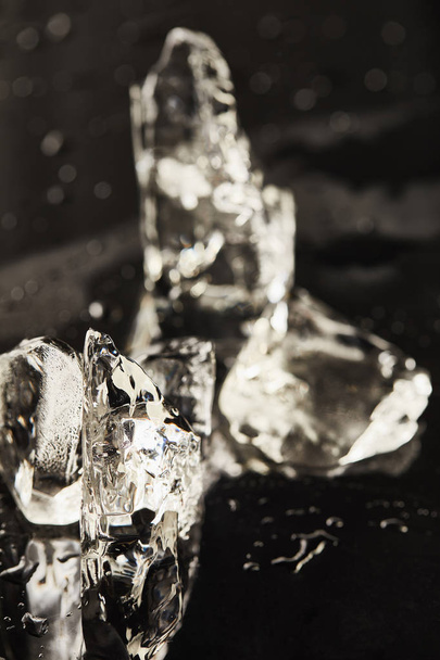 transparent melting ice cubes with drops on black surface - 写真・画像