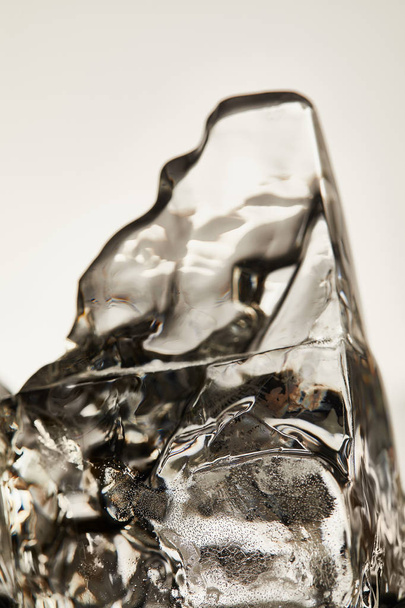 close up view of transparent melting ice cube isolated on grey - Foto, imagen
