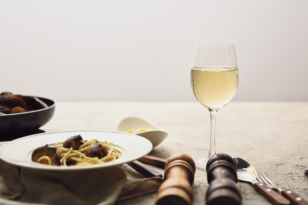 вкусная паста с морепродуктами подается с белым вином, изолированным на сером
 - Фото, изображение