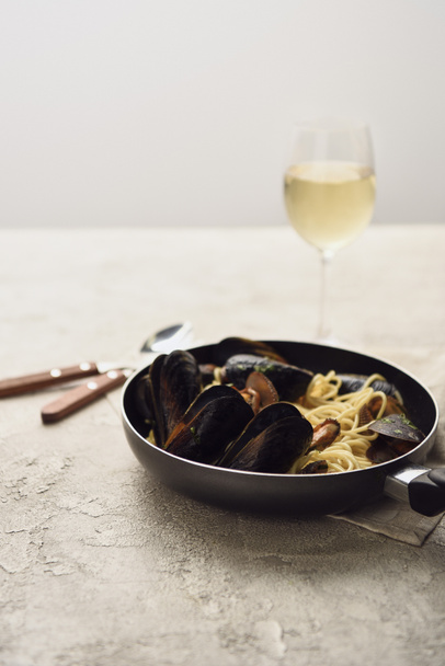 selective focus of tasty Italian pasta with seafood served in frying pan isolated on grey - Photo, Image