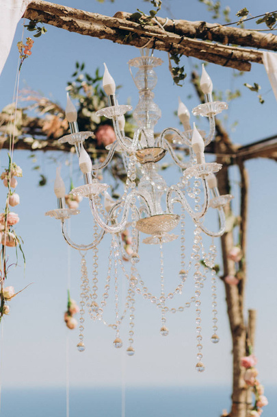 Fragment of a wedding arch for ceremony decorated with flowers and a chandelier. - Foto, Bild