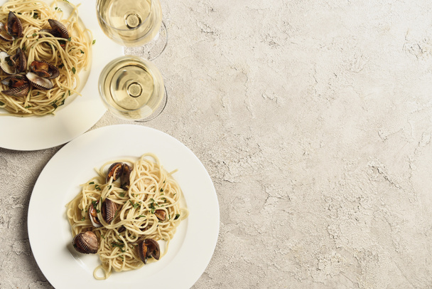 top view of delicious pasta with seafood served with white wine in glasses on textured grey surface with copy space - Photo, Image