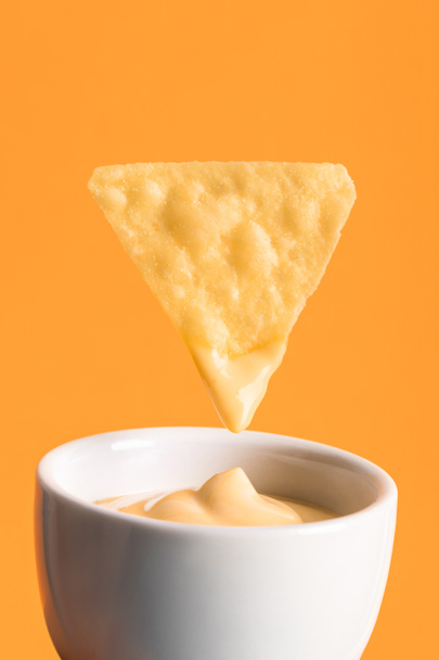オレンジ、メキシコ料理に分離されたボウルにチーズソースとクリスピーコーンナチョ - 写真・画像