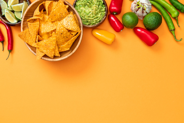 Widok z góry meksykański nachos, guacamole i przyprawy na pomarańczowym tle z kopią przestrzeni - Zdjęcie, obraz