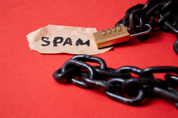 Beschermen tegen junk mail of spam e-mail en ongevraagde brief. Inscriptie op een stuk papier en een ketting met een slot - Foto, afbeelding