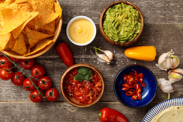 ylhäältä näkymä Meksikon nachoja tarjoillaan guacamole, juustokastike ja salsa puinen maalaismainen pöytä
 - Valokuva, kuva