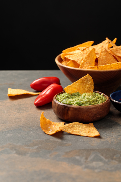 Mexican nachos with guacamole and chili peppers on stone table isolated on black - Photo, Image