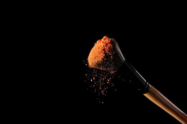 cosmetic brush with orange powder on black background - Photo, Image
