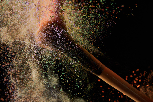 cosmetic brush with colorful powder explosion on black background - Photo, Image