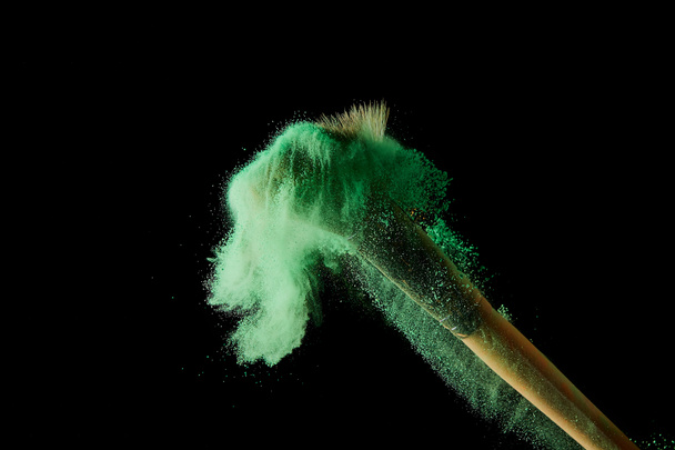 cosmetic brush with colorful green powder on black background - Photo, Image