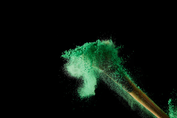 cosmetic brush with colorful green powder explosion on black background - Photo, Image
