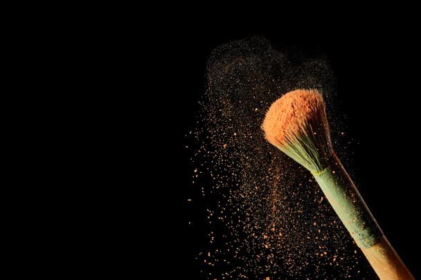 cosmetic brush with colorful orange powder on black background - Foto, Imagem