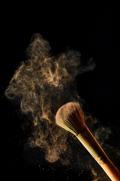 cosmetic brush with colorful light powder on black background - Fotó, kép