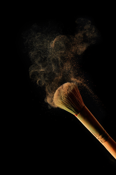 cosmetic brush with light powder on black background - Fotó, kép