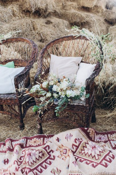 Wedding asymmetrical stylish bouquet with roses on a boho wicker chair. - Zdjęcie, obraz