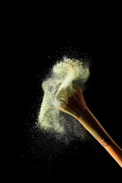 cosmetic brush with bright yellow colorful dust on black background - Photo, Image